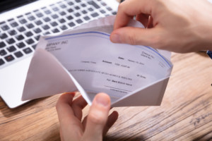 Person's Hand Removing Paycheck From The Envelope